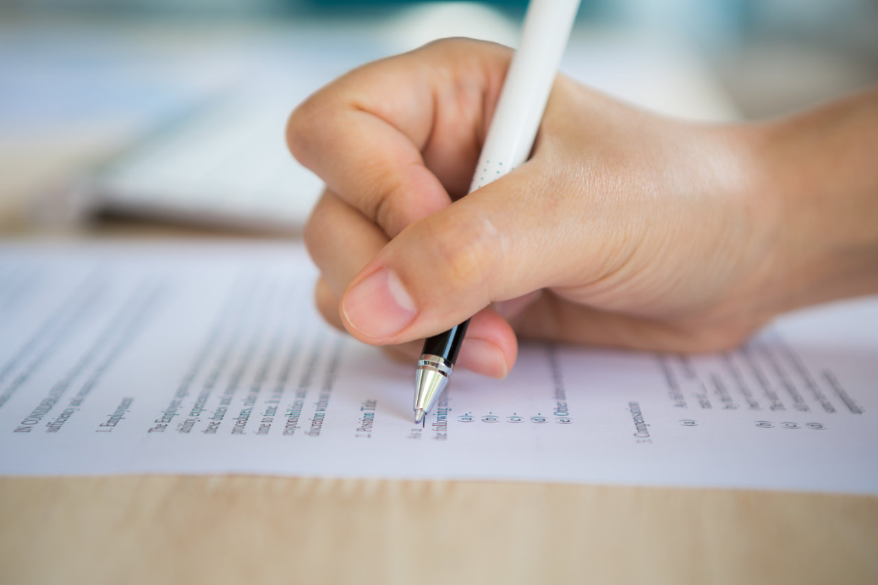Mão segurando caneta para responder prova de concurso público para Servidor Público Federal