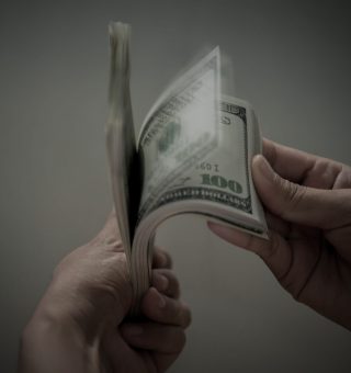Notas de dólar na mão representando o salário do Procurador-Geral da República